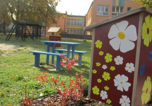 "Brzęczący zakątek" z domkiem dla owadów ozdobiony naklejonymi kwiatami wśród wrzosów w ogrodzie przedszkolnym